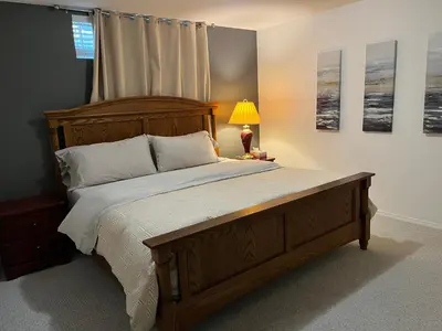 a bedroom with a large wooden bed and a lamp at Licensed spacious basement suite with one king-size bed in Chilliwack