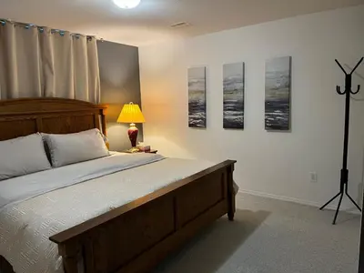a bedroom with a bed and a lamp and pictures on the wall at Licensed spacious basement suite with one king-size bed in Chilliwack