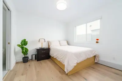 a white bedroom with a bed and a window at Steveston Village Bed and Breakfast in Richmond