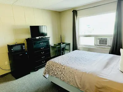 a bedroom with a bed and a television and a window at Beaverlodge Motor Inn in Beaverlodge