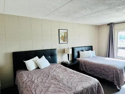 a hotel room with two beds and a window at Beaverlodge Motor Inn in Beaverlodge