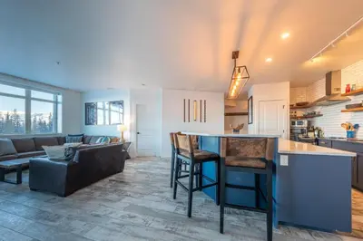 a kitchen and living room with a bar and a couch at Fully Renovated Ski-in/out Loft with Private Hot Tub! in Golden