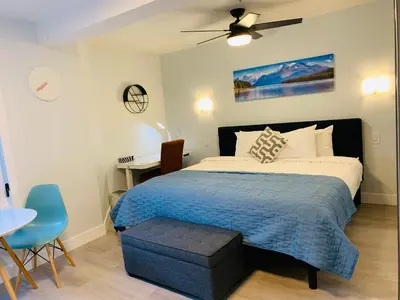 a bedroom with a bed with a blue blanket and a table at A Romantic Studio with Full Kitchen & AC-141 in Canmore