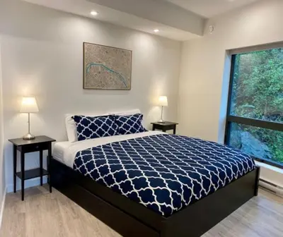a bedroom with a bed and two lamps and a window at J and Js in Bowen Island