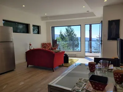 a living room with a red couch and a large window at J and Js in Bowen Island