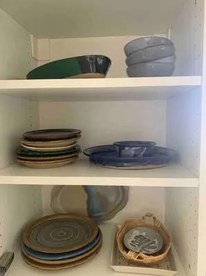 two shelves of plates and bowls in a closet at Tiny House Big View in Chilliwack