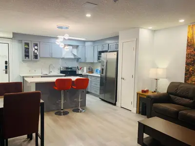 a kitchen and living room with red chairs and a couch at Romantic 1-Bedroom Serviced Apartment Kitchen & AC 143 in Canmore