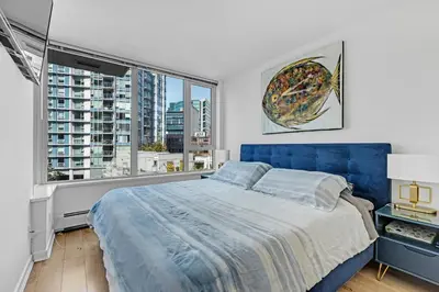 a bedroom with a blue bed and a large window at Gastown Downtown Apartment very central in Vancouver