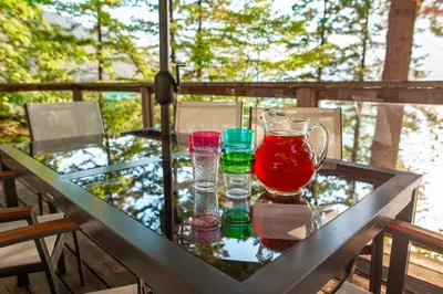 a glass table with four glasses and a pitcher on it at The Overlook, Luxury Lakeside Home with Dock in Harrison Hot Springs