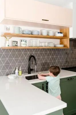 a young boy standing in a kitchen next to a sink at Mount Rundle Hideaway - Pool Hot Tub in Canmore