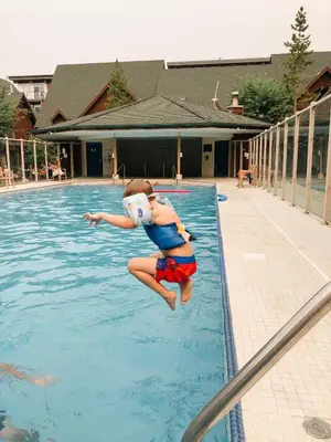 a young girl jumping into a swimming pool at Mount Rundle Hideaway - Pool Hot Tub in Canmore