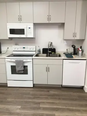 a kitchen with white cabinets and a stove and a sink at The Purple Door Carriage House in Lantzville
