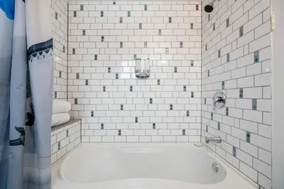 a white tiled bathroom with a bath tub at Triceratops Landing I Fire Place I Games I Netflix in Drumheller
