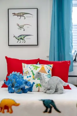 two stuffed dinosaurs are sitting on a bed at Triceratops Landing I Fire Place I Games I Netflix in Drumheller