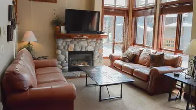 a living room with leather couches and a fireplace at Woodhaven #18 by Bear Country in Sun Peaks