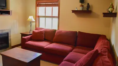 a living room with a red couch and a table at Woodhaven #18 by Bear Country in Sun Peaks