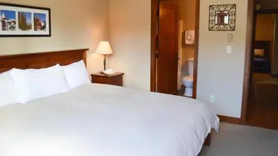 a bedroom with a white bed and a bathroom at Woodhaven #18 by Bear Country in Sun Peaks