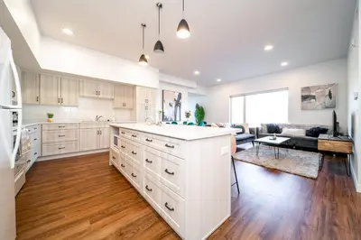 a kitchen with white cabinets and a living room at Exotic,LUSH,Rainforest,CR,Suite,King,U/G,Wifi in Edmonton