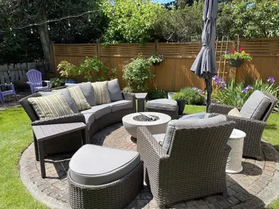 an outdoor patio with wicker chairs and an umbrella at Fisher House Victoria Bed and Breakfast in Victoria