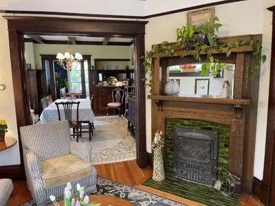 a living room with a fireplace and a table at Fisher House Victoria Bed and Breakfast in Victoria