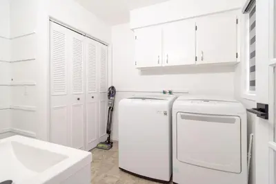 a white kitchen with a refrigerator and a sink at Spacious & Modern by the Beach in White Rock