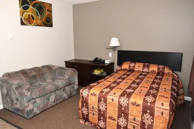 a hotel room with a bed and a couch at Blue Bell Inn in Fort Nelson