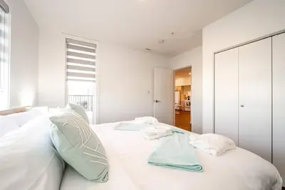 a white bedroom with two towels on a bed at Steamy Romantic Greek Corneer Suite King U/G Wifi in Edmonton