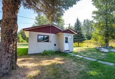 a small house with a red roof next to a tree at Downie Cottage by Revelstoke Vacations in Revelstoke