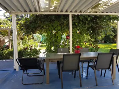 a wooden table and chairs under a pergola at private single room in a house in Richmond
