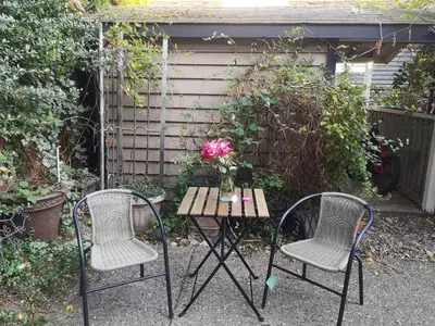 two chairs and a table with a vase of flowers on it at Jimmy B&B in Surrey