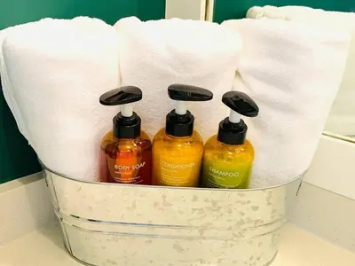 a bucket with four bottles of soap and towels at King Garden Suite/20 mins to Dwntwn Vancouvr/PetOk in North Vancouver