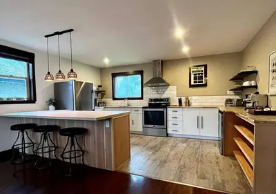 a kitchen with white cabinets and a island with bar stools at Two Bedroom House by Snow Valley Lodging in Fernie