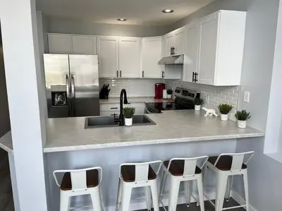a kitchen with white cabinets and a counter with stools at Bearcub Chalet in Big White