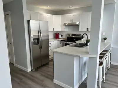 a kitchen with white cabinets and a stainless steel refrigerator at Bearcub Chalet in Big White