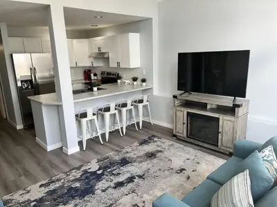 a living room with a kitchen with a large television at Bearcub Chalet in Big White