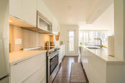 a white kitchen with a sink and a stove at Sunset Beach Walk 2BD+2BA+1PRK Yaletown in Vancouver