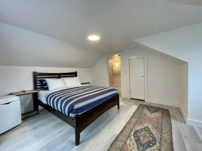a bedroom with a bed with a blue and white striped blanket at Salt Loft - Oceanfront, Hot Tub And Firepit! in Ucluelet
