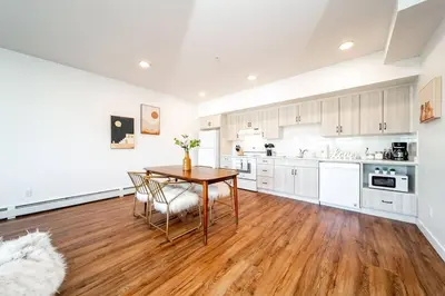 a kitchen with white cabinets and a wooden table and chairs at Hot Arabaian NightsCornerPNHSEkingWifiU/G in Edmonton