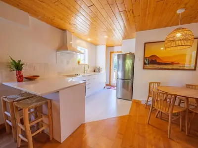 a kitchen with a wooden ceiling and a table and chairs at The Perch Modern 2 Bed Cabin with Patio and Hot Tub in Ucluelet