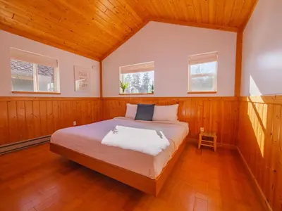 a bedroom with a bed in a room with wooden walls at The Perch Modern 2 Bed Cabin with Patio and Hot Tub in Ucluelet