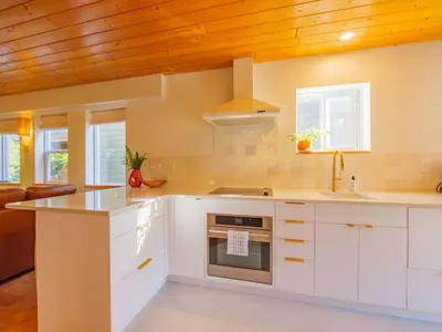 a kitchen with white cabinets and a stove at The Perch Modern 2 Bed Cabin with Patio and Hot Tub in Ucluelet