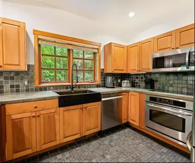 a kitchen with wooden cabinets and stainless steel appliances at Ski In/Ski Out Luxury Home w/ jacuz/ fireplace in Whistler