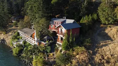 an aerial view of a house on a hill next to the water at Salishan Chief Suite by EMR Vacation Rentals in Cowichan Bay