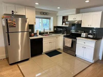 a kitchen with white cabinets and a stainless steel refrigerator at Private room in a Shared house in Vancouver