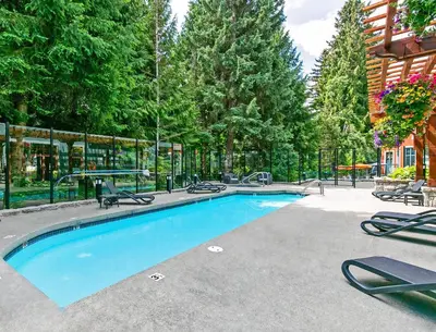 a swimming pool with lounge chairs and trees at Alpenglow Lodge Cozy Studio with Den by MVA in Whistler
