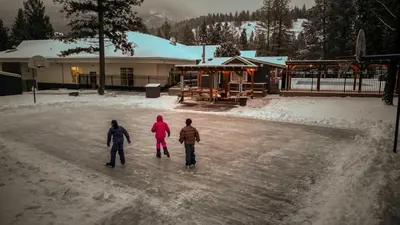 three people walking in the snow in front of a building at RidgeView Resort in Radium Hot Springs