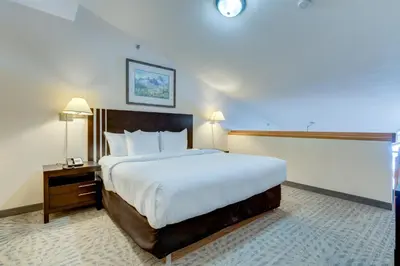 a hotel room with a large bed and a night stand at Chateau Canmore in Canmore