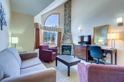 a living room with a couch and a desk and a fireplace at Chateau Canmore in Canmore