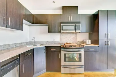 a kitchen with stainless steel appliances and wooden cabinets at Stylish 1BR, Stampede & Free Parking by Doorbed in Calgary