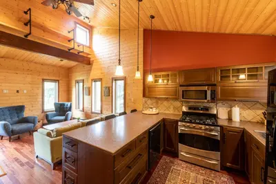 a kitchen with wooden cabinets and a stove top oven at The Qu INN - Cozy Cabin in Parson